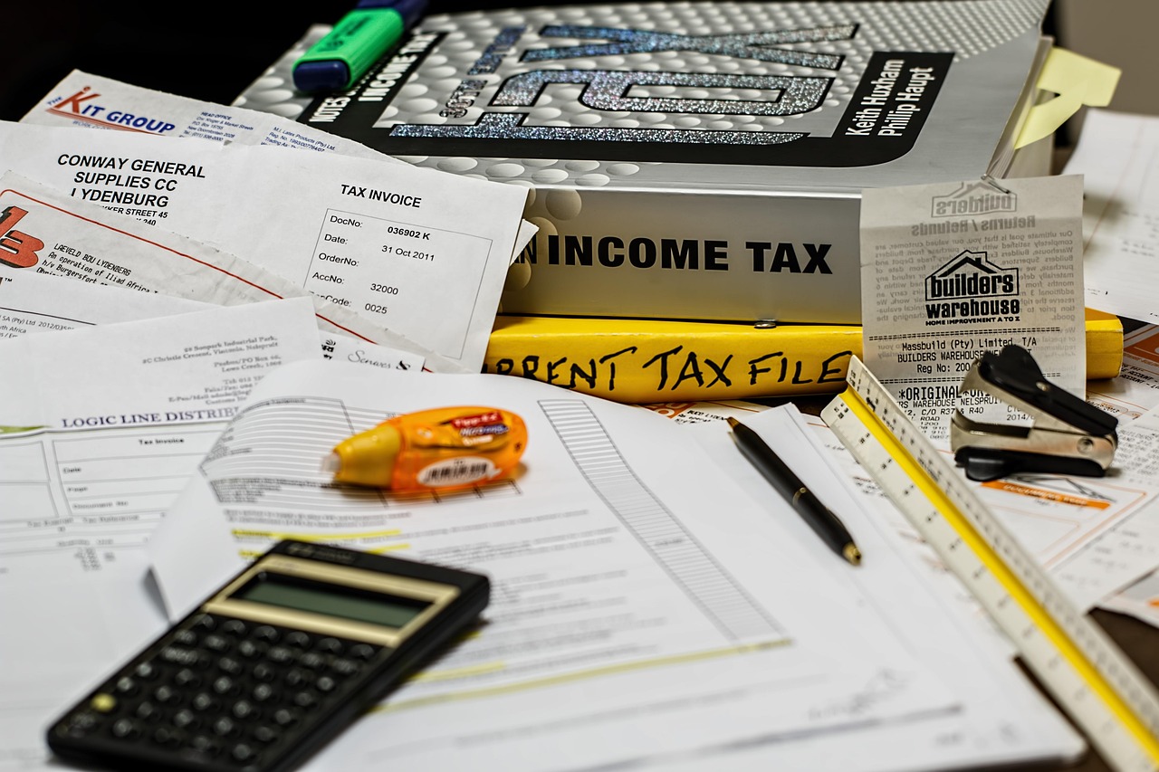 Calculadora e formulários de imposto de renda sobre a mesa — consulta e pagamento do 3º lote de restituição do IRPF 2026